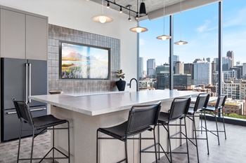 a kitchen with a large island with stools and a large window with a city view