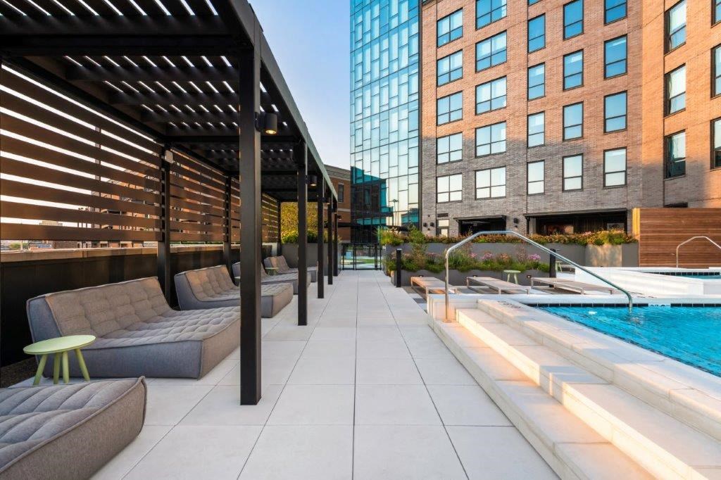 a pool with lounge chairs and a stool next to a building