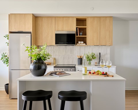 A kitchen with a white countertop and black stools.