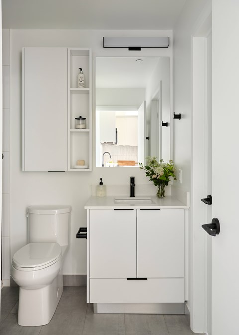 A white bathroom with a toilet, sink, and mirror.