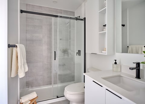 A white bathroom with a toilet, sink, and shower.