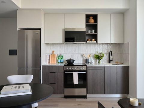 A modern kitchen with a stainless steel refrigerator and a black oven.