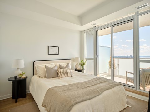 A bedroom with a large bed and a view of the ocean through the sliding glass doors.