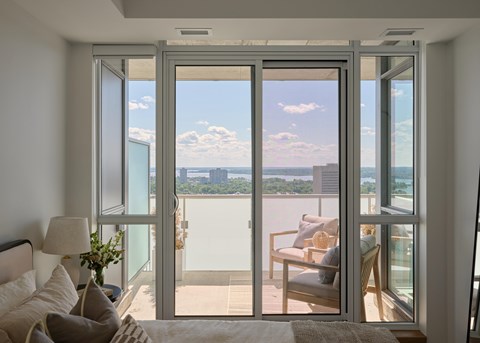 A bedroom with a large window overlooking a cityscape.