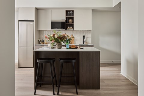 A kitchen with a white countertop and black bar stools.
