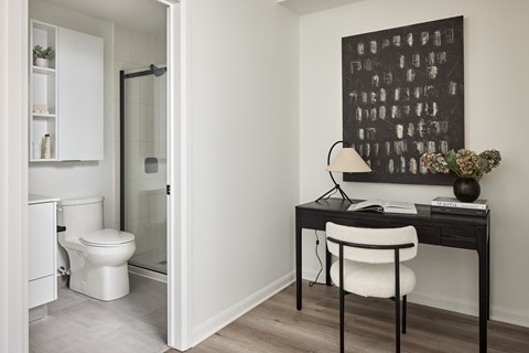 A bathroom with a toilet and a desk with a chair.