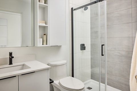 A white bathroom with a toilet, sink, and shower.