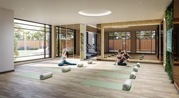 A yoga class is taking place in a spacious room with a large window.
