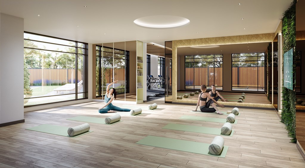 A yoga class is taking place in a spacious room with a large window.