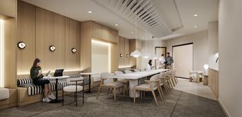 A woman is sitting on a bench in a room with wooden walls and a long table with chairs.