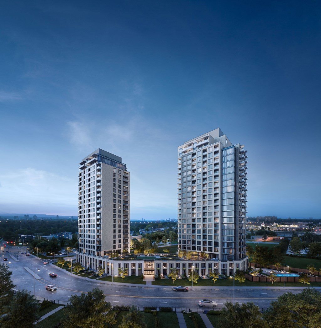 Two modern high-rise buildings are situated in a roundabout with a road and cars passing by.