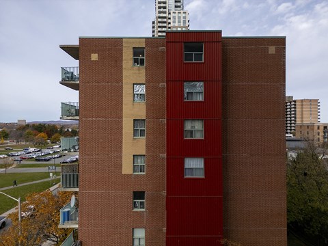 a tall building with a red facade and a city in the background