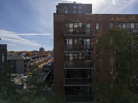 a tall brick building with balconies and a city in the background