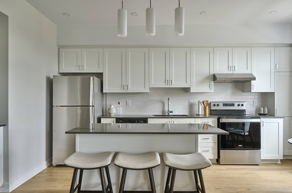 a kitchen with white cabinets and a island with three stools