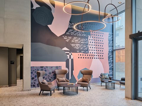 A modern lobby with a large mural and comfortable seating.