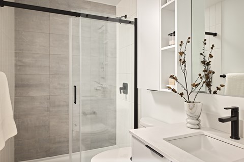 A white sink with a vase of dried flowers on top of it.