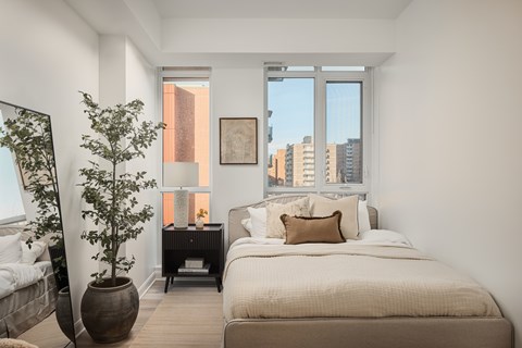 A bedroom with a large bed and a potted plant.