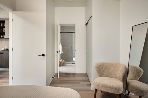 A bedroom with a bed, chair and mirror.