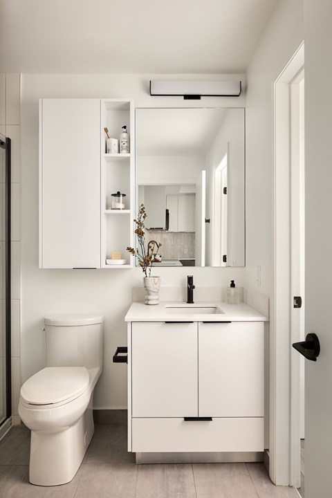 A white bathroom with a toilet, sink, and medicine cabinet.