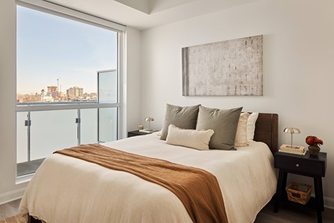A bedroom with a large bed and a view of the city.