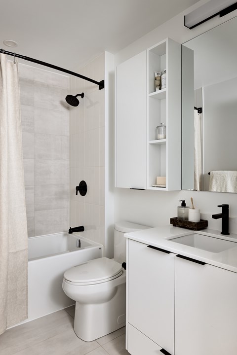 A white bathroom with a toilet, sink, and shower.