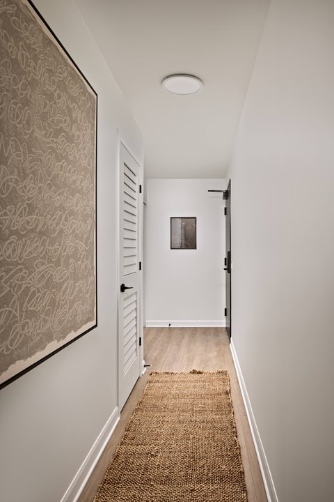 A hallway with a rug on the floor and a door on the right.