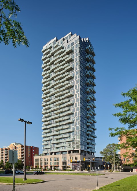 A tall, modern glass building stands in the middle of a city street.