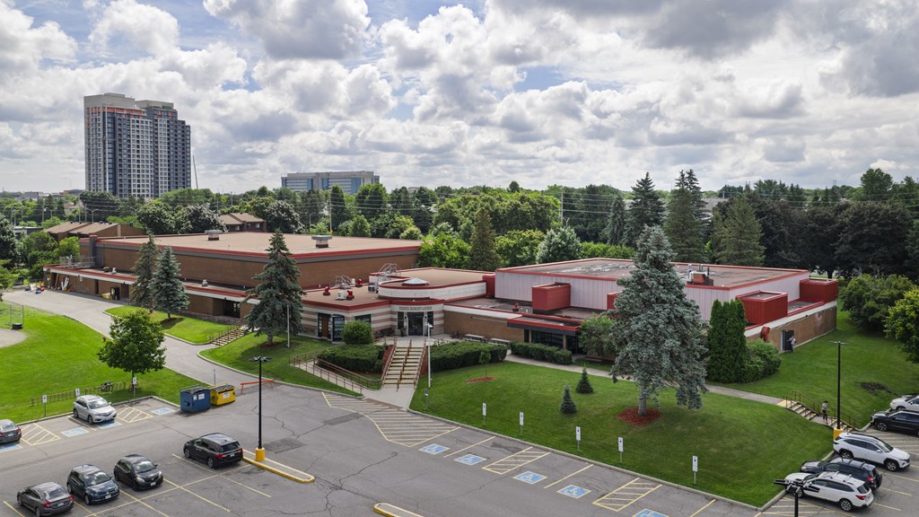 A parking lot in front of a building with a large red roof.