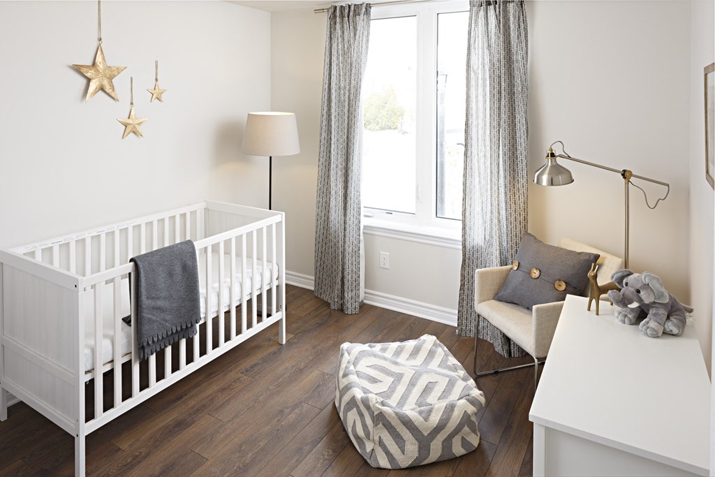 a baby nursery with a crib and a table with a chair and a window