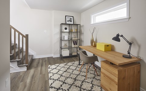 a home office with a wooden desk and chair in a room with a staircase