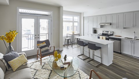 a living room with a couch and a table in front of a kitchen