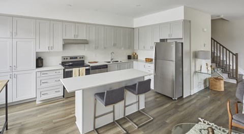 a white kitchen with a white island and stainless steel appliances