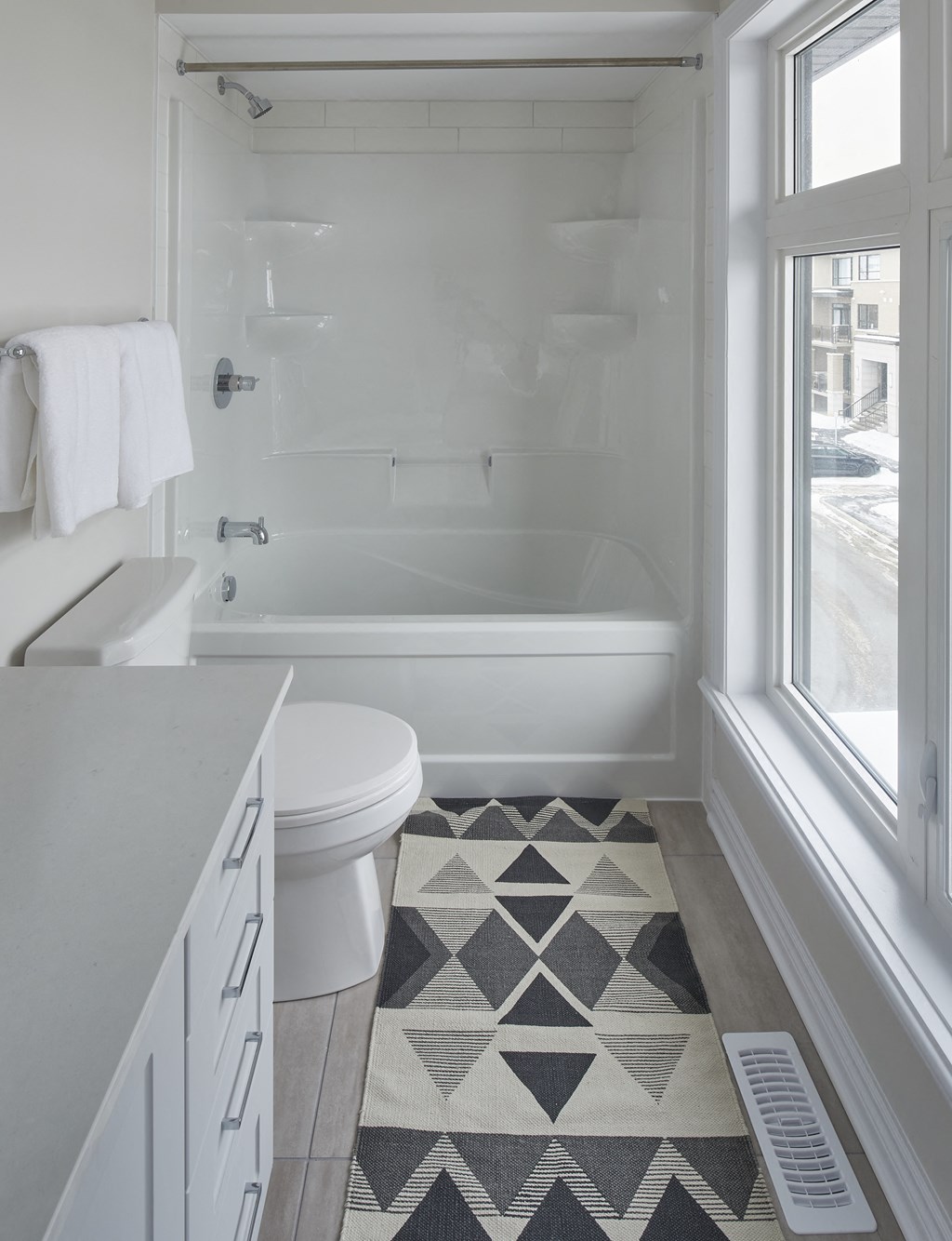 a white bathroom with a white toilet and a tub and a window