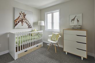 a nursery with a crib with a giraffe painting on the wall and a chair