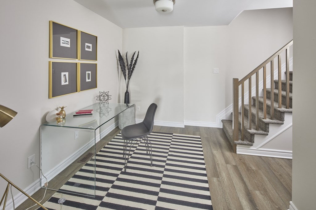 a living room with a glass desk and a stairwell