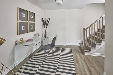 a living room with a glass desk and a stairwell