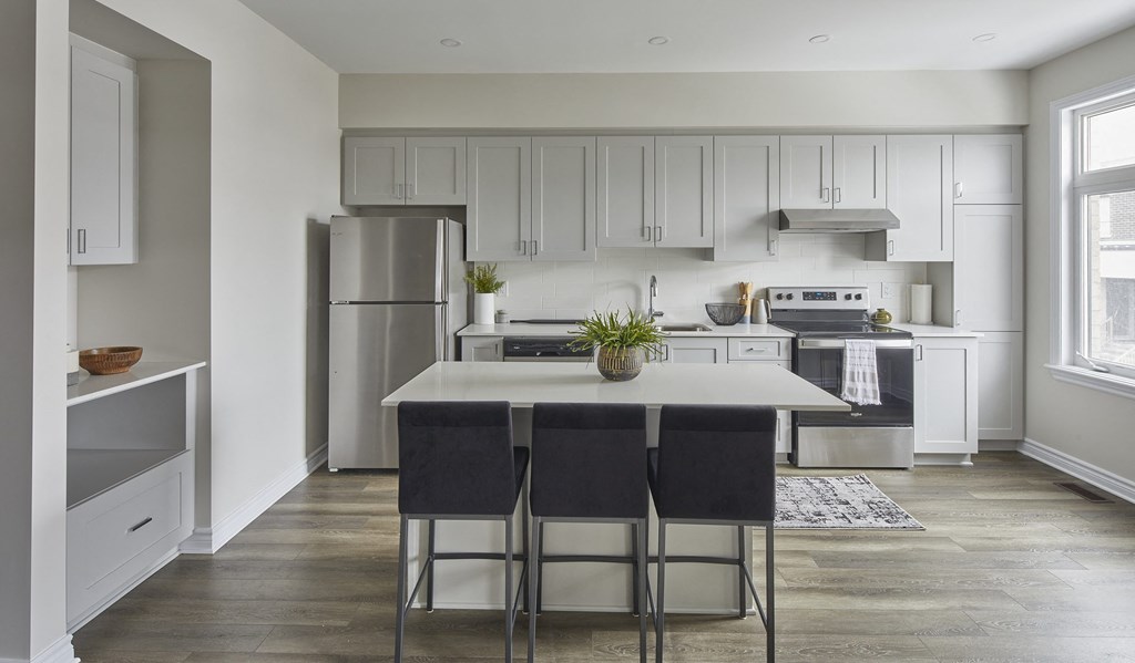 a kitchen with white cabinets and a white island with three stools