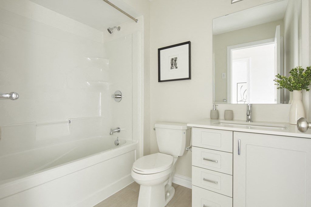 a white bathroom with a toilet and a bath tub