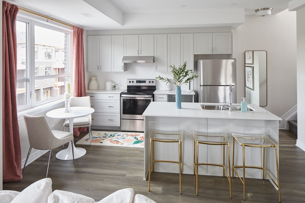 a kitchen with white cabinets and a white island with gold chairs