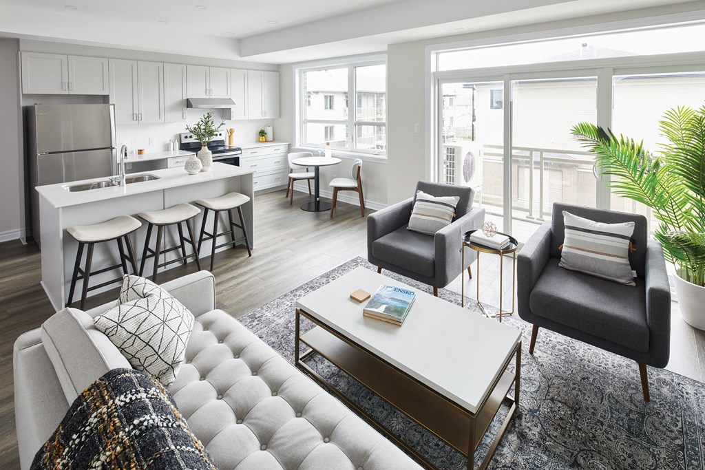 a living room with a kitchen and a couch and chairs