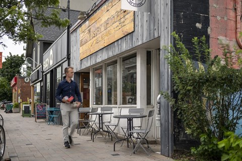 a man walks down a sidewalk in front of a restaurant