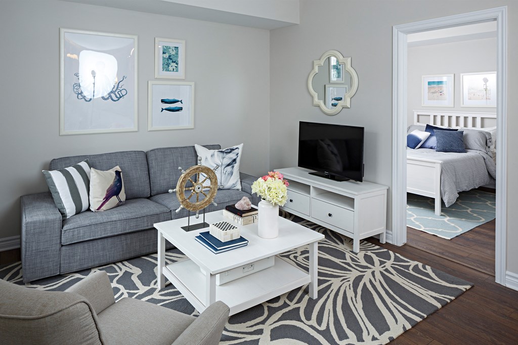 a living room with a gray couch and a white coffee table and a television