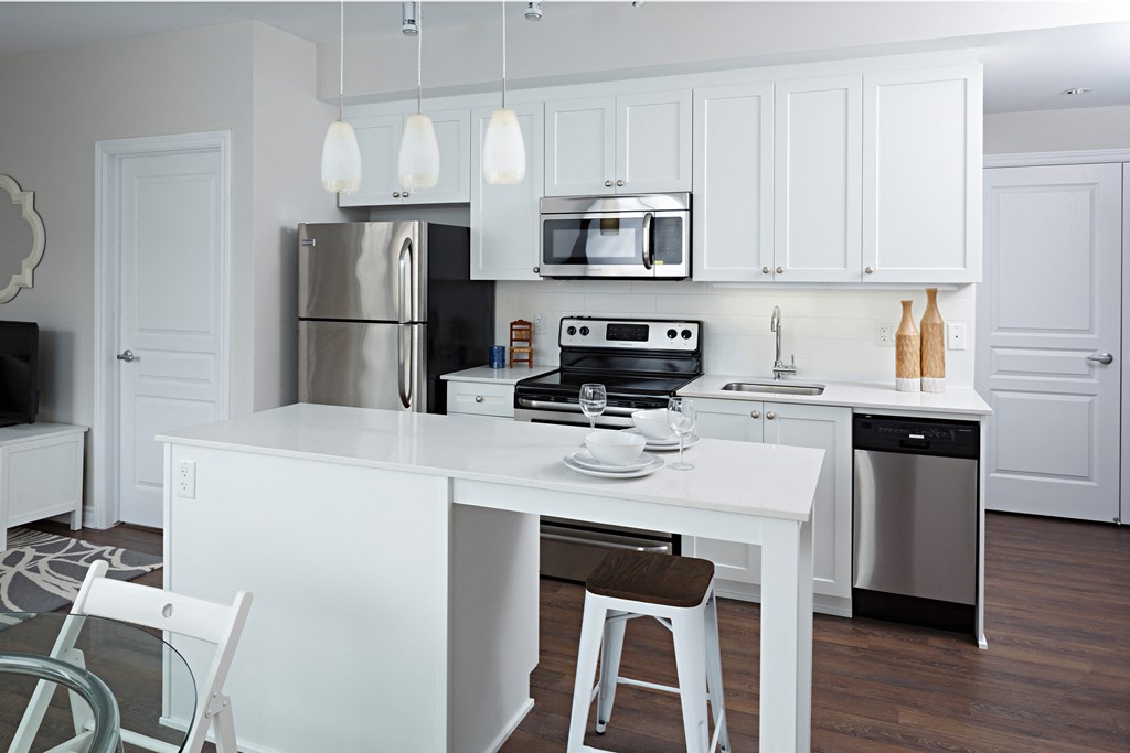 a white kitchen with a white island and stainless steel appliances