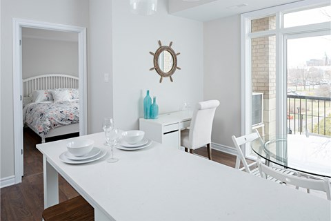 a dining room with a white table and chairs and a bedroom with a bed