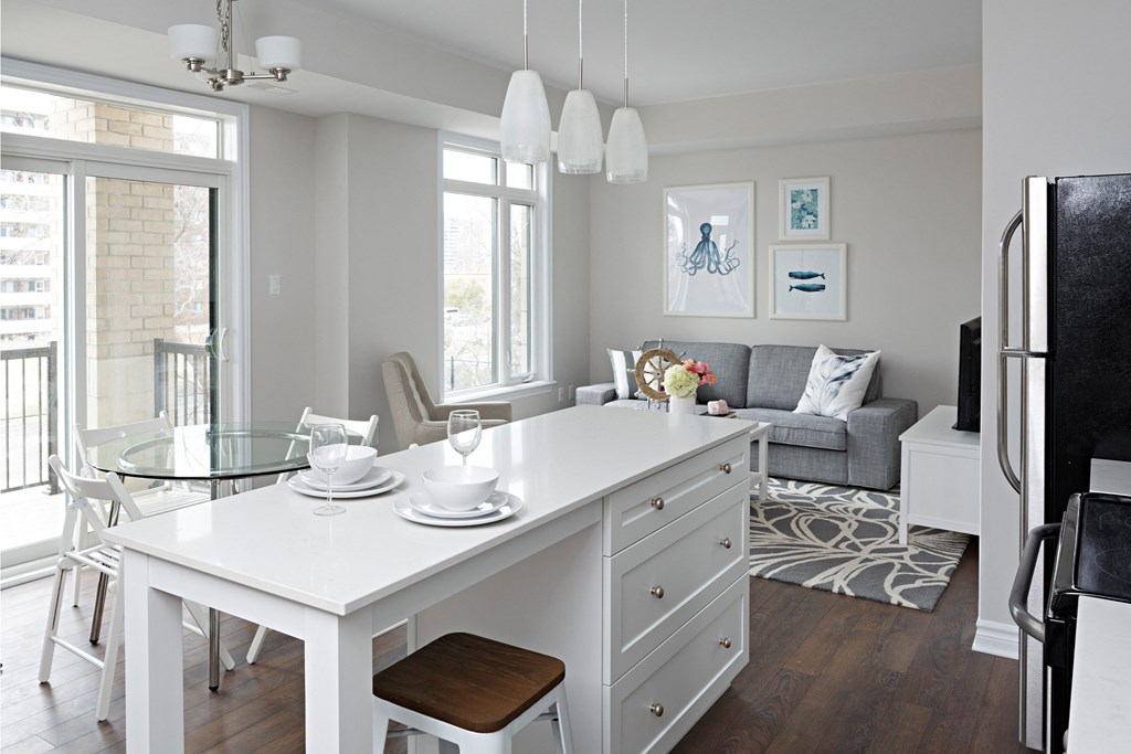 a kitchen and living room with a white island and a glass table