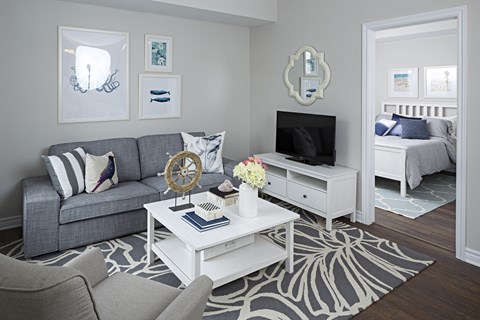 a living room with a gray couch and a white coffee table and a television
