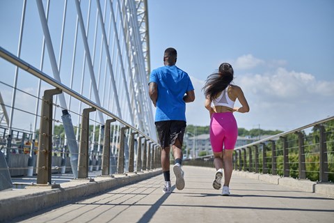 a man and woman running on a bridge