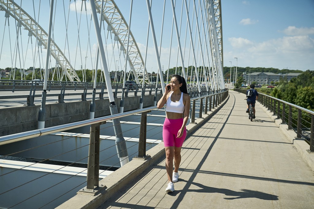 a woman walking on a bridge while talking on her cell phone