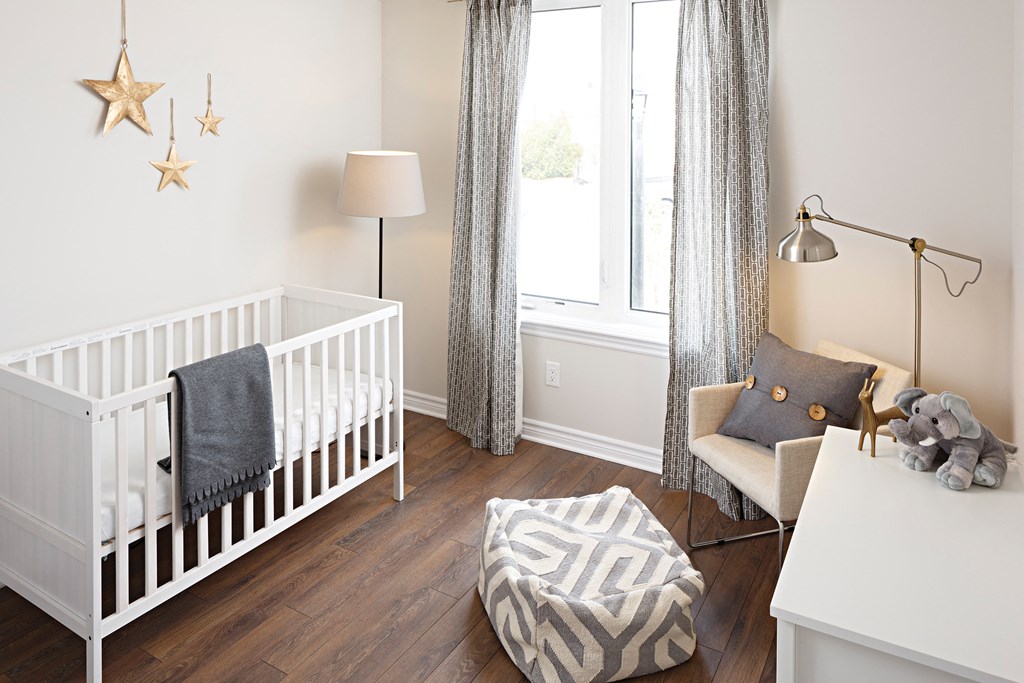 a baby room with a crib and a chair and a window