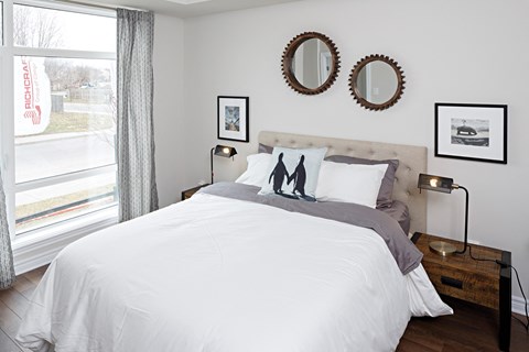 a bedroom with a bed and two mirrors on the wall